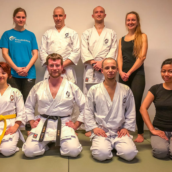 Mehrere Personen sitzen nach dem letzten Karate Training des Jahres auf dem Bodem im Dojo.