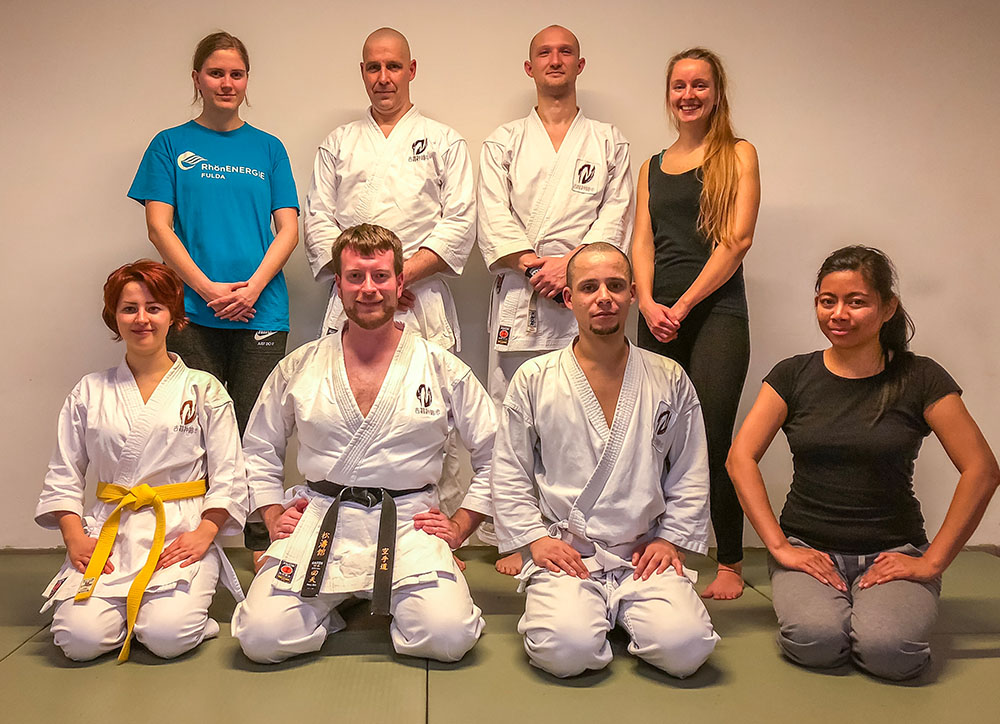 Mehrere Personen sitzen nach dem letzten Karate Training des Jahres auf dem Bodem im Dojo.