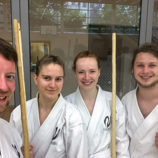 Vier Personen mit Kobudo Holzstäben (Bo).